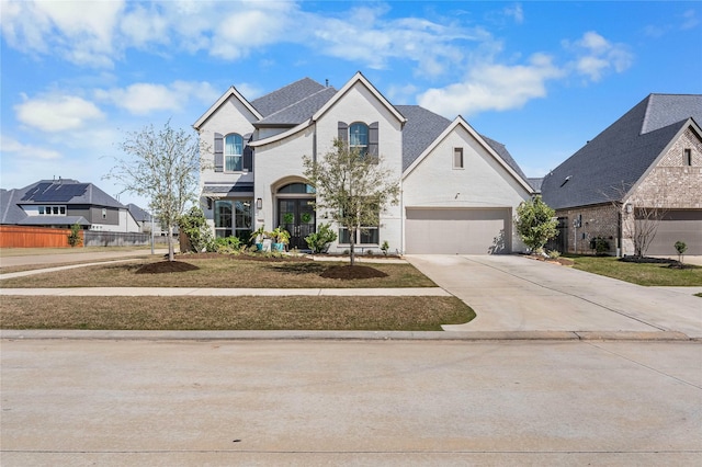 french country home featuring concrete driveway and brick siding