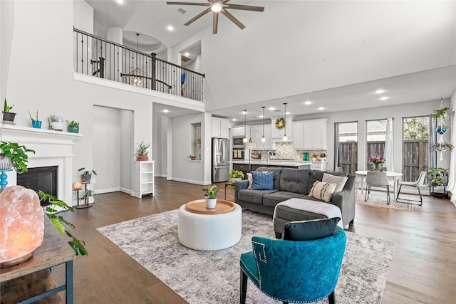 living room with dark wood finished floors, recessed lighting, visible vents, a glass covered fireplace, and baseboards