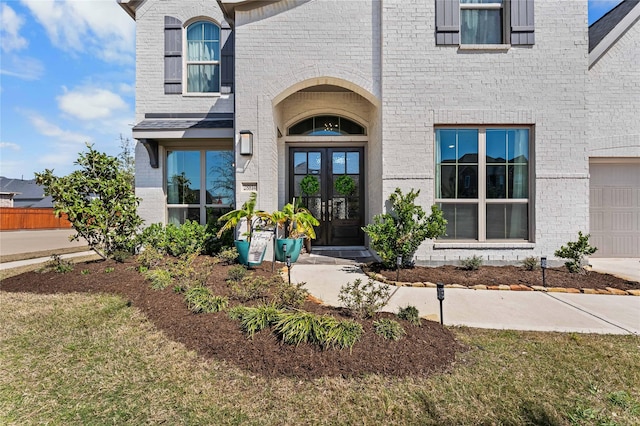 property entrance featuring a garage, brick siding, and french doors