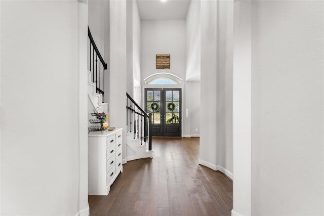 entrance foyer with french doors, dark wood finished floors, a towering ceiling, baseboards, and stairs