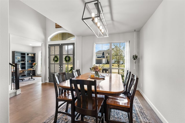 dining space featuring french doors, stairway, wood finished floors, and baseboards