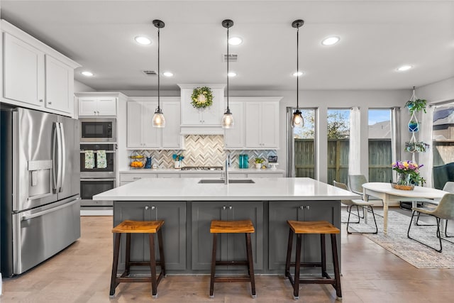 kitchen with appliances with stainless steel finishes, light countertops, visible vents, and a sink