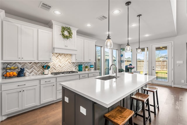 kitchen featuring a breakfast bar, an island with sink, a sink, and visible vents