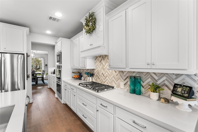 kitchen with stainless steel appliances, light countertops, visible vents, white cabinetry, and premium range hood