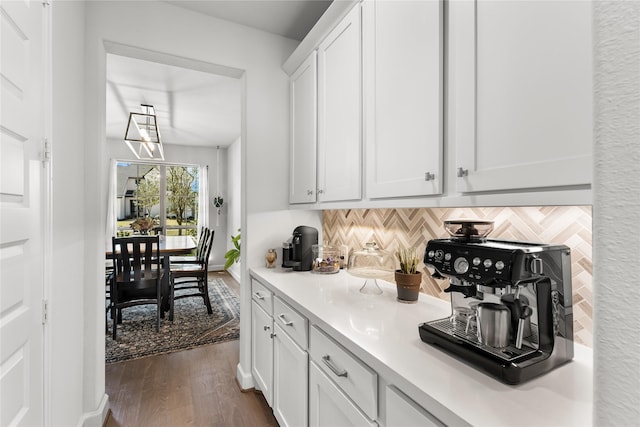 kitchen featuring baseboards, white cabinets, dark wood-type flooring, light countertops, and backsplash