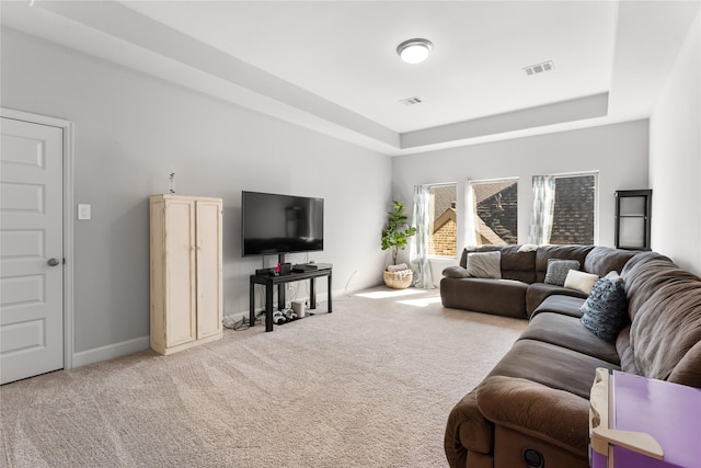 carpeted living area with a tray ceiling, visible vents, and baseboards