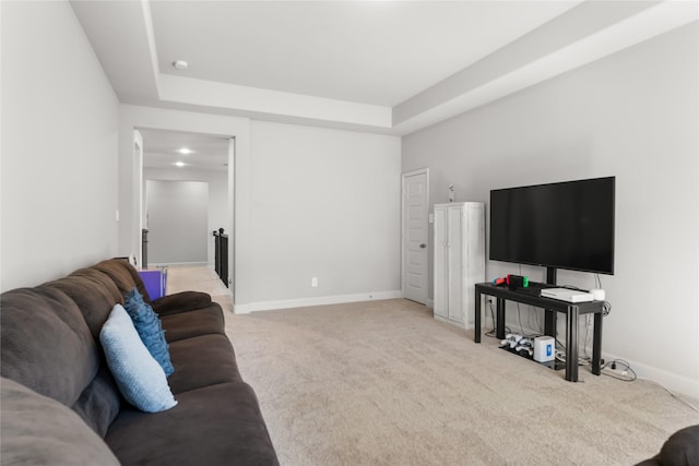 carpeted living room with a tray ceiling and baseboards