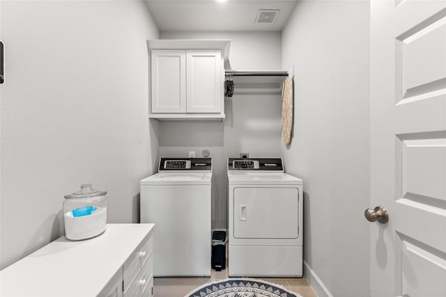 laundry room featuring light tile patterned floors, cabinet space, visible vents, washing machine and dryer, and baseboards