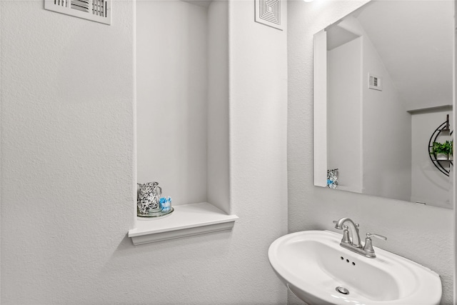 bathroom with visible vents, a sink, and a textured wall