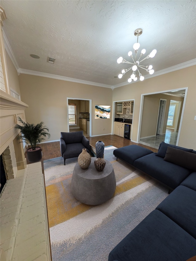 living room with a brick fireplace, crown molding, a textured ceiling, and an inviting chandelier