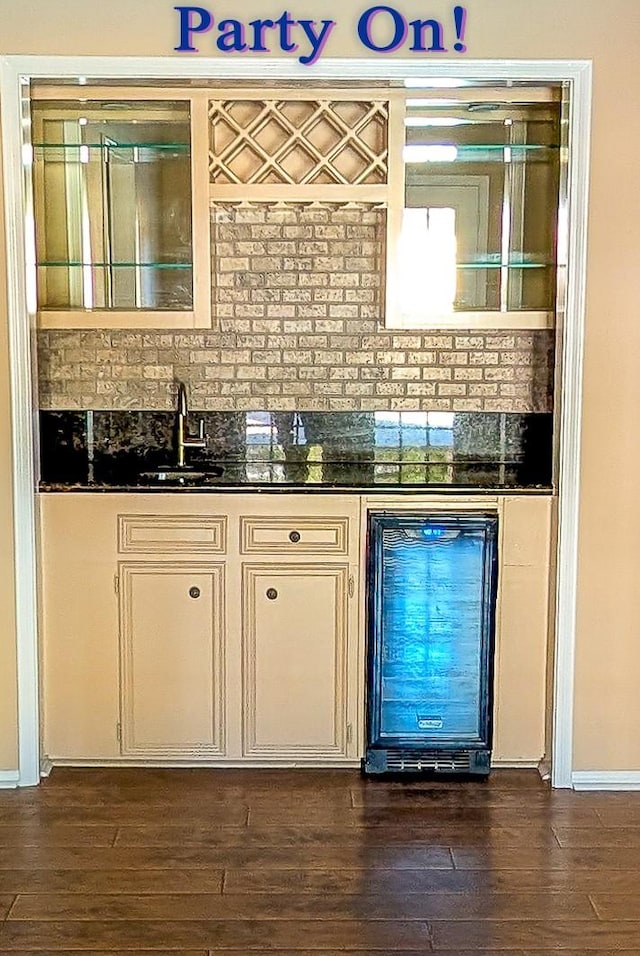 bar with beverage cooler, dark wood-type flooring, a sink, and wet bar