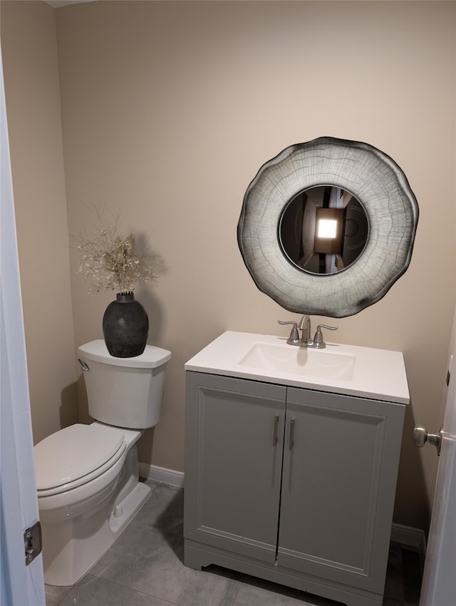 bathroom with tile patterned flooring, baseboards, vanity, and toilet