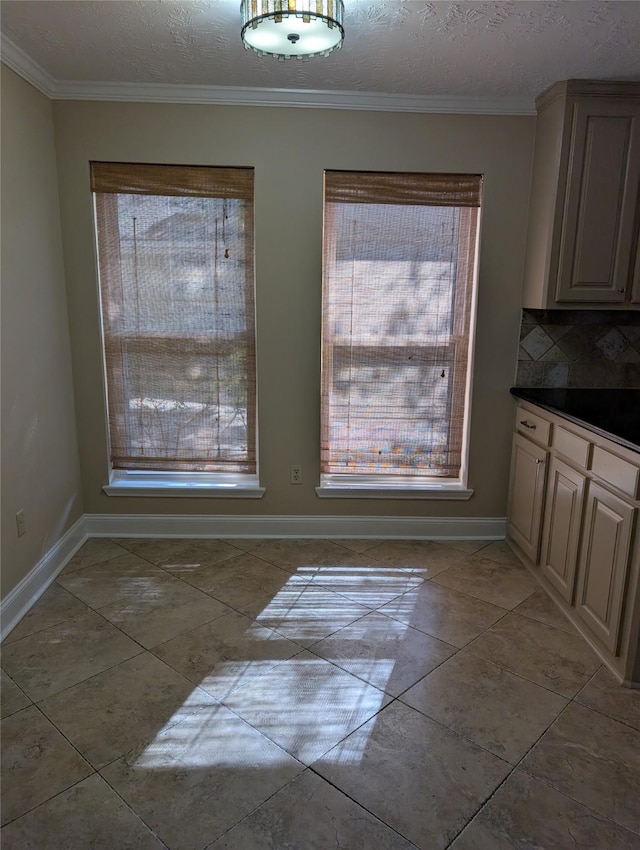 unfurnished dining area featuring a textured ceiling, baseboards, and crown molding