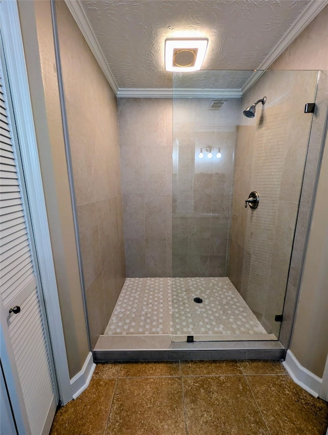 full bath with a textured ceiling, ornamental molding, and a shower stall