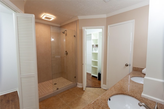 full bath with a shower stall, a textured ceiling, ornamental molding, and a sink