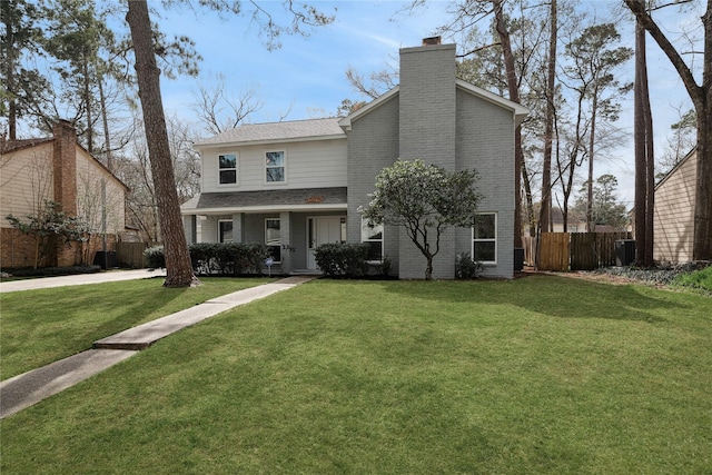 view of front of home with brick siding, a front lawn, a chimney, and fence