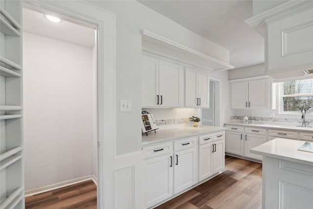 kitchen with light wood finished floors, baseboards, decorative backsplash, white cabinets, and light countertops