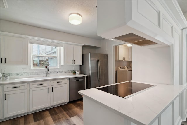 kitchen with dark wood-style floors, appliances with stainless steel finishes, a peninsula, washing machine and dryer, and backsplash