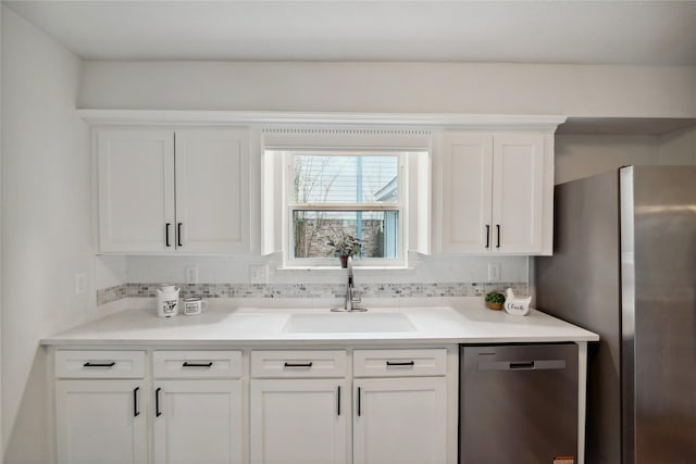 kitchen featuring stainless steel appliances, a sink, white cabinetry, and decorative backsplash