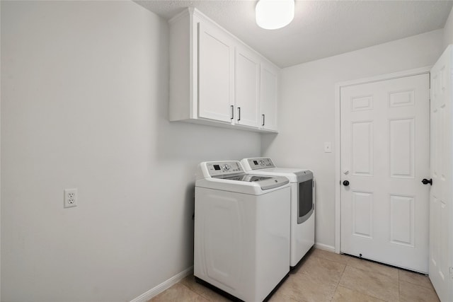 clothes washing area with baseboards, light tile patterned floors, cabinet space, and washer and dryer