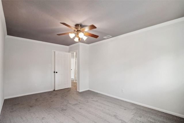 unfurnished room featuring carpet floors, crown molding, visible vents, a ceiling fan, and baseboards