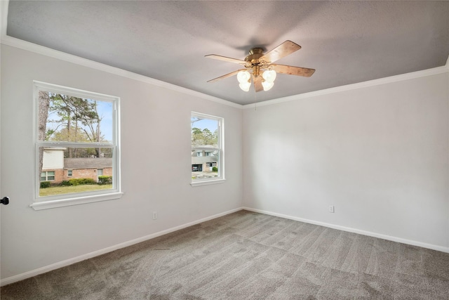 carpeted spare room featuring a ceiling fan, baseboards, and crown molding