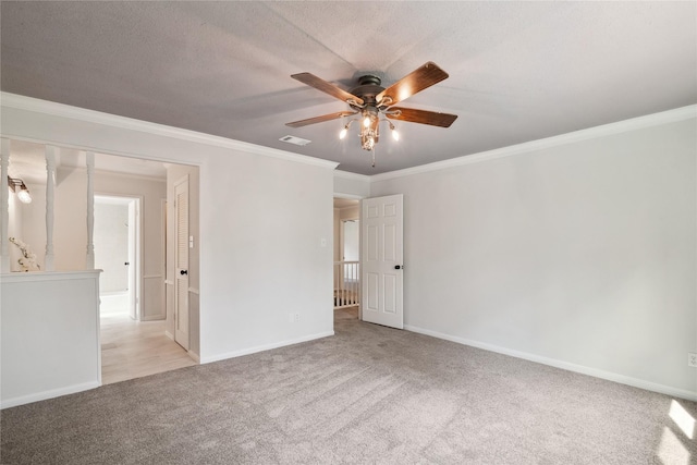 carpeted spare room featuring crown molding, visible vents, ceiling fan, a textured ceiling, and baseboards