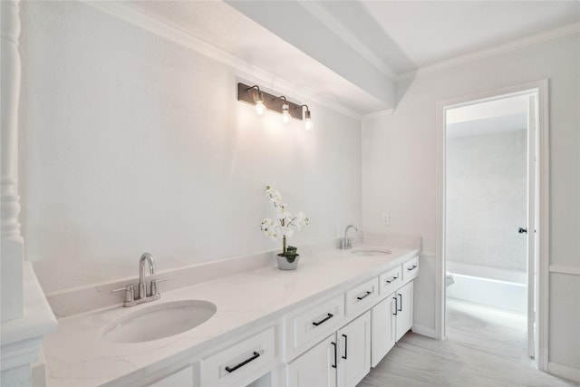 full bathroom with double vanity, ornamental molding, a sink, and a bathtub