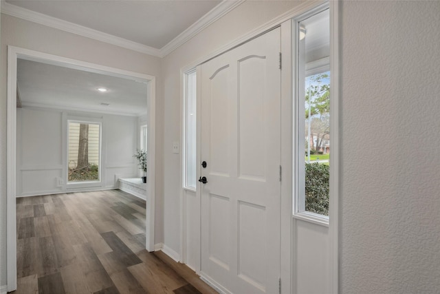 foyer entrance with baseboards, a textured wall, dark wood-type flooring, and crown molding