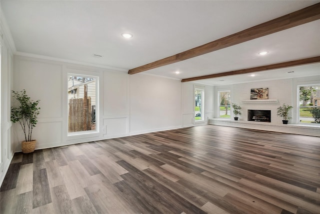 unfurnished living room featuring a decorative wall, a fireplace, wood finished floors, ornamental molding, and beamed ceiling