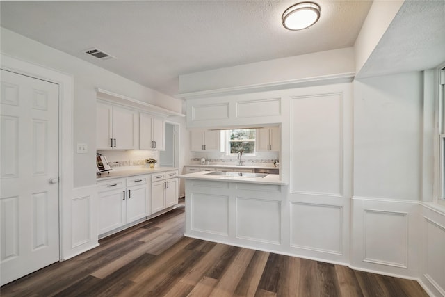 kitchen featuring dark wood-style flooring, visible vents, white cabinets, light countertops, and backsplash