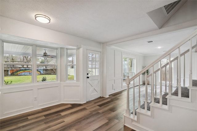 foyer featuring visible vents, stairway, dark wood-style flooring, a textured ceiling, and a decorative wall