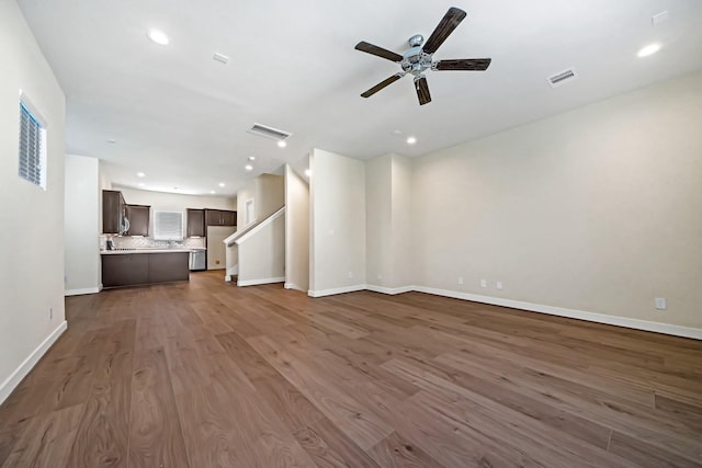 unfurnished living room with baseboards, visible vents, and dark wood-style flooring