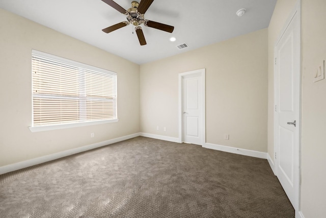 unfurnished bedroom with ceiling fan, dark carpet, visible vents, and baseboards