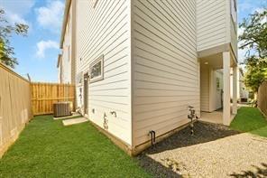 view of side of property featuring cooling unit, a fenced backyard, and a lawn