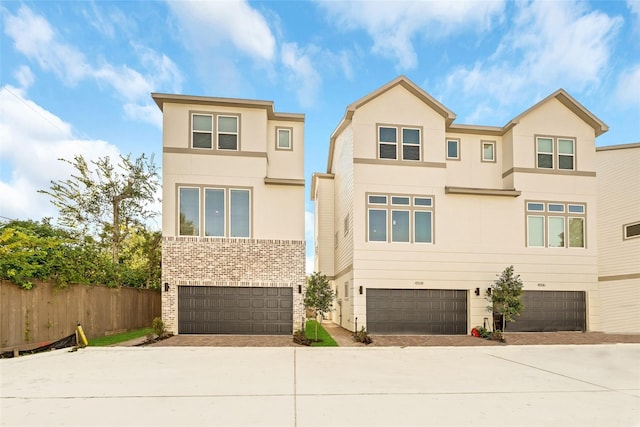 view of front of house featuring an attached garage, fence, and stucco siding