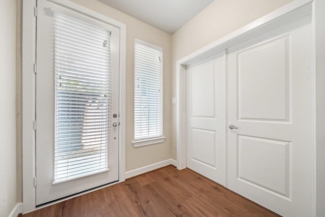 doorway to outside featuring baseboards and wood finished floors