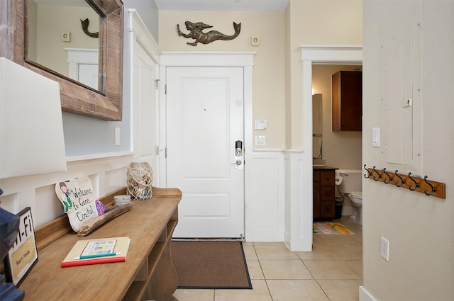 entryway with light tile patterned floors and wainscoting