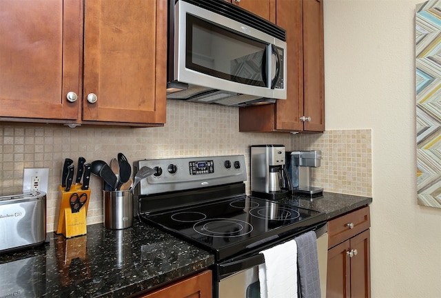 kitchen featuring decorative backsplash, dark stone counters, brown cabinetry, and appliances with stainless steel finishes