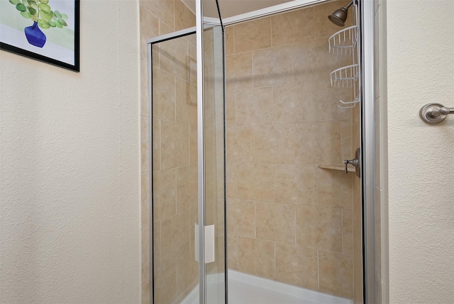 bathroom featuring a textured wall and a stall shower