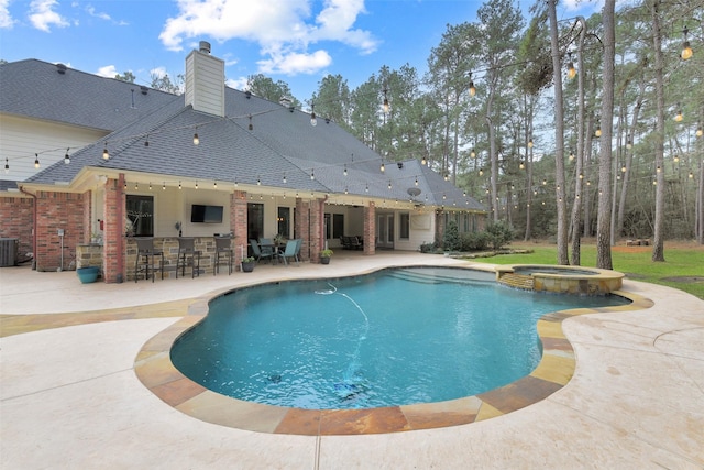 view of pool with outdoor dry bar, central AC, a pool with connected hot tub, and a patio