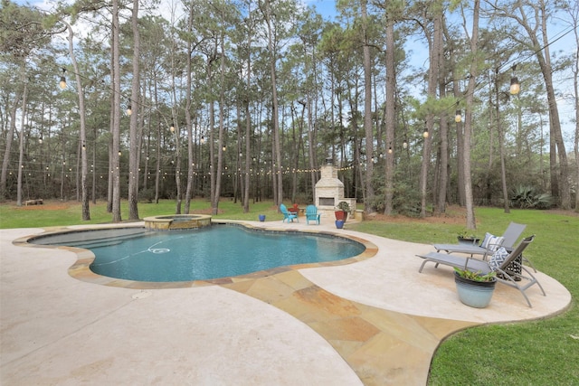 view of pool featuring a lawn, a pool with connected hot tub, an outdoor stone fireplace, and a patio