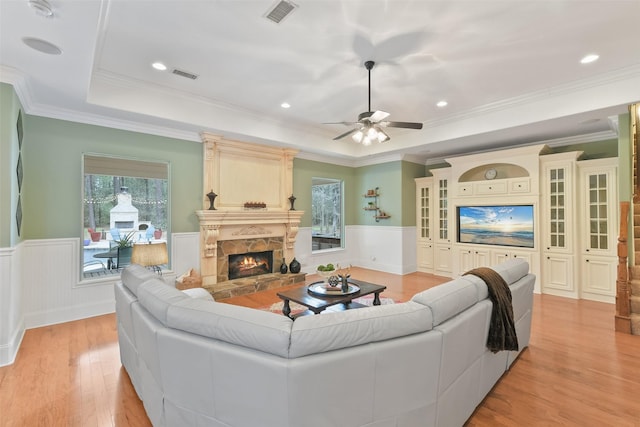 living area featuring a wainscoted wall, a raised ceiling, a fireplace, and visible vents