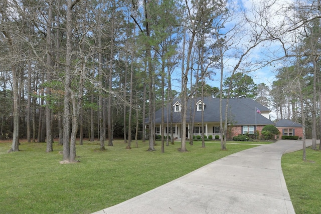 cape cod-style house with brick siding, concrete driveway, and a front yard