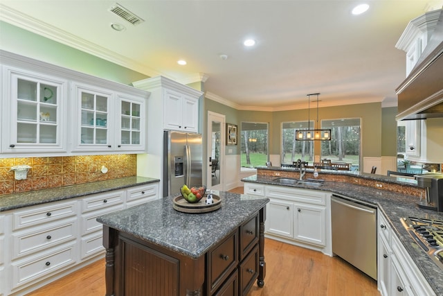 kitchen with ornamental molding, appliances with stainless steel finishes, white cabinetry, and a sink