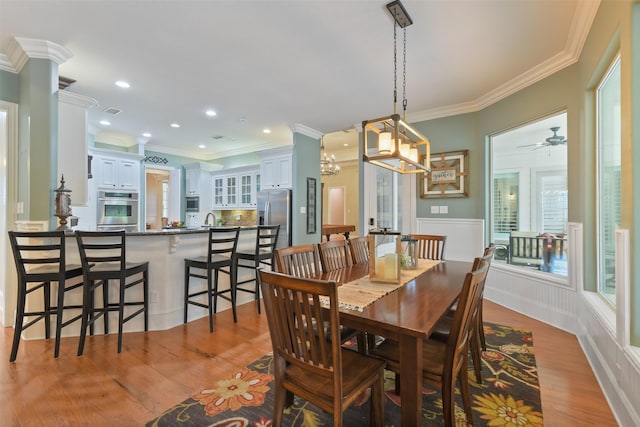 dining area with recessed lighting, wood finished floors, wainscoting, and ornamental molding