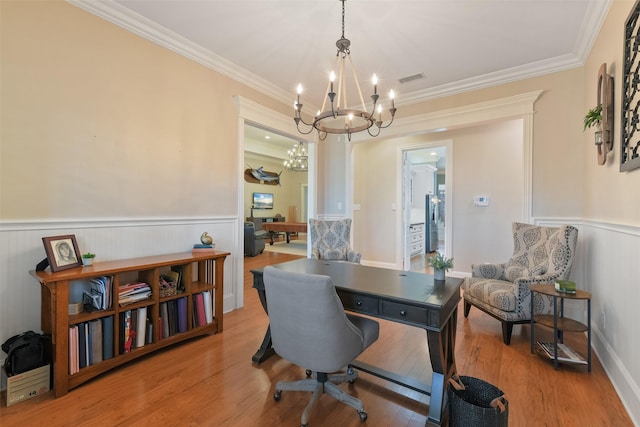 office area with a wainscoted wall, crown molding, visible vents, and wood finished floors