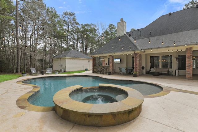 view of swimming pool with a patio, an outbuilding, a pool with connected hot tub, and outdoor dry bar