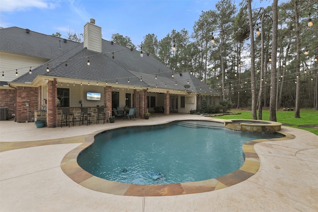 view of swimming pool with outdoor dry bar, central AC, a pool with connected hot tub, and a patio