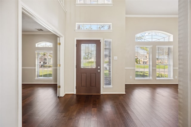 foyer entrance featuring baseboards, ornamental molding, dark wood finished floors, and a healthy amount of sunlight